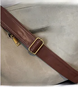 Detail view of grey twill fabric tote with smooth brown leather adjustable strap