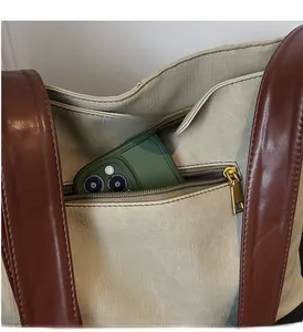 Close-up of the large tote bag interior showing the zipper pocket with a phone