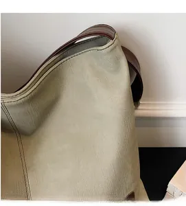 Close-up of beige twill fabric texture and brown leather strap on a minimalist tote bag