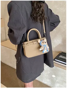 Close-up of khaki crossbody square bag with cute teddy bear charm and twin handles