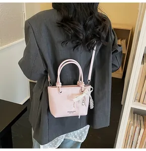 Dettaglio borsa tote rosa con ciondolo a fiocco in pizzo bianco e tracolla regolabile