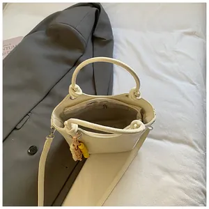 Detail einer cremeweißen Leder-Eimertasche mit geknoteten Griffen und Innentasche