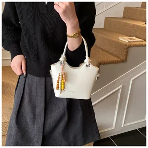 Detailansicht der weißen Bucket Bag aus Kunstleder mit Perlenanhänger und Goldbeschlägen