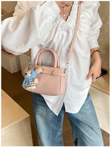 Pink pebbled leather crossbody bag detail with cute teddy bear charm and top handle