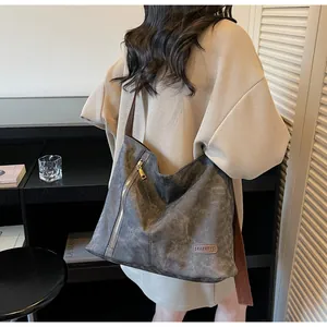 Detailed close-up of dark grey canvas tote bag with brown leather strap and metal zipper