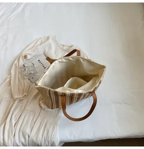 Detailed view of the straw tote bag's open top with cream lining and inner pocket