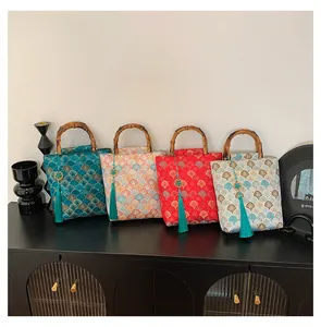 Detail of four jacquard handbags with bamboo handles and tassels on a black cabinet