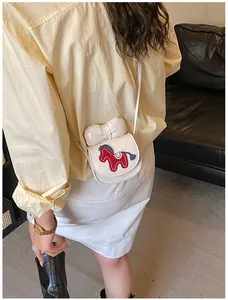 Detail van een witte mini-schoudertas met ruitpatroon, strik en paardborduursel
