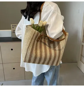 Detailed shot of large striped straw tote bag worn over shoulder with leather handles