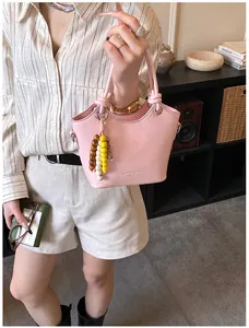 Rosa Eimertasche mit dekorativen Knoten und bunten Perlenanhängern für den Alltag