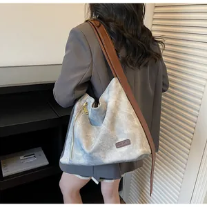 Detail of grey vintage tote bag with wide brown shoulder strap and brand leather tag