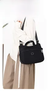 Detail of black nylon crossbody bag featuring wide adjustable strap and circular logo