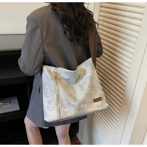 Detail of blue faux leather tote bag showing SHANHEYCA logo and golden zipper decor