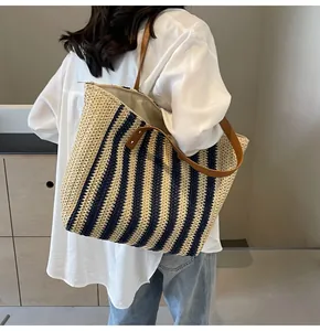 Detail of striped straw tote bag showing brown faux leather straps and zipper closure