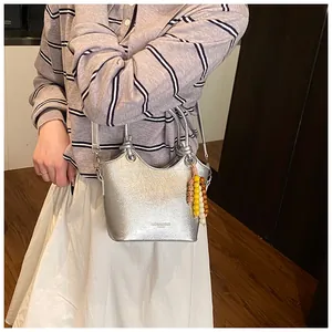 Silberne Beuteltasche mit Metallic-Effekt und bunter Perlenkette im Detail gezeigt