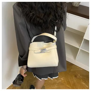 Detail of cream-colored lychee leather bucket bag with silver metal twist lock closure