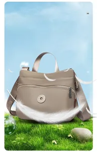 Detail of lightweight khaki crossbody bag shown in a cloud-like soft outdoor setting