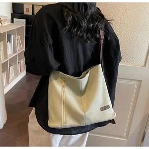 Detail of large canvas tote bag with side zipper and branded leather patch on shoulder