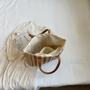 Straw woven tote beach bag with brown leather handles and zipper closure for women