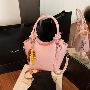 Rosa Eimer-Handtasche aus Kunstleder mit Perlenanhänger und verstellbarem Gurt