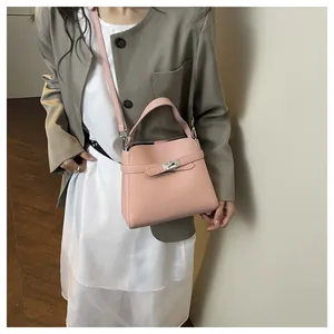 Detail of light pink pebble leather bucket bag with silver twist lock and strap