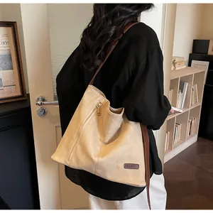 Detail of apricot suede tote bag featuring metallic zipper and brown leather shoulder strap