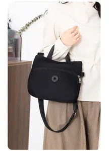 Detail of the adjustable shoulder strap and zip pockets on this black nylon crossbody bag