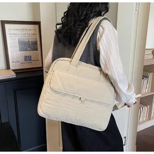 Close-up of cream quilted shoulder bag with soft padding and functional front pocket