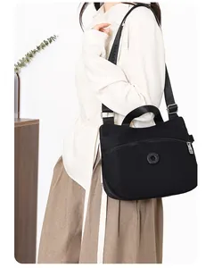 Side view of a black nylon crossbody bag with multiple pockets worn by a model