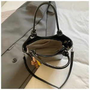 Glänzende schwarze Beuteltasche mit Knotengriff und farbigem Perlenanhänger