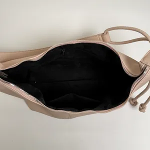 Top view of the spacious inner compartment with zip pocket and beige leather texture