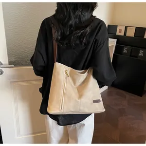 Detail of minimalist beige tote bag with metallic zipper and slender brown shoulder strap