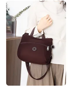 Detail of coffee crossbody bag with wide logo strap and water-resistant nylon texture