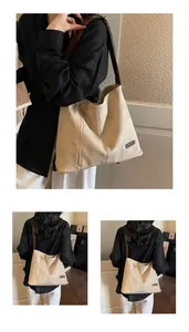 Detail of a large beige tote bag with brown straps and functional vertical zipper pocket
