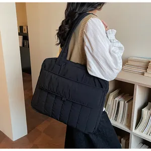 Detail of black quilted tote bag showing vertical stitching and spacious front flap pocket