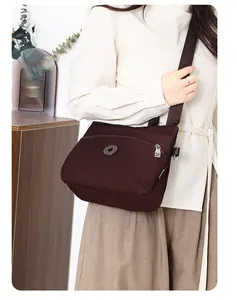 Detail of dark coffee nylon crossbody bag with wide logo strap and front zipper pocket