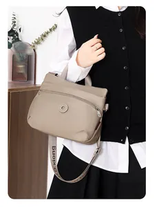 Detailed view of khaki nylon crossbody bag featuring curved zipper pocket and logo strap