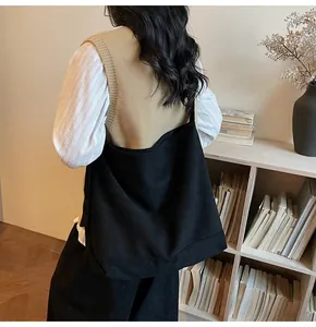Detail of a large black suede tote bag styled with a minimalist white and khaki outfit