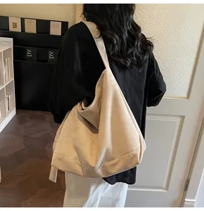 Rear view of a large beige suede tote bag styled on a shoulder in a cozy setting