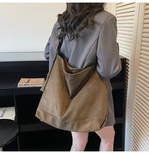 Close-up of a large dark brown suede hobo bag with a magnetic metal buckle closure