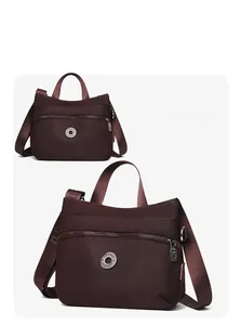 Detail view of coffee nylon crossbody bag with multi-zipper layers and wide strap