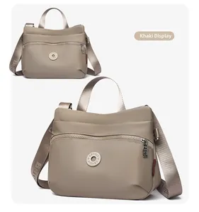 Detail view of khaki nylon shoulder bag with adjustable strap and branding logos