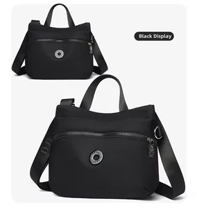 Detail of black crossbody bag featuring adjustable wide lettered strap and front zip pocket