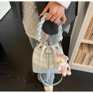 Detail of light blue plaid bucket bag with braided handle and cute plush charm