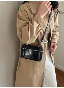 Détail du sac à main noir brillant avec fermetures éclair argentées et bandoulière réglable