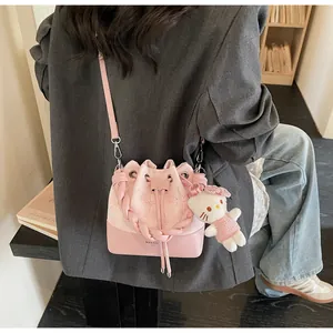 Detail view of a pink bucket bag with star embroidery and a plush kitten charm
