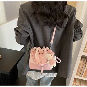 Detail of pink bucket bag with woven handle and plush kitten charm on model
