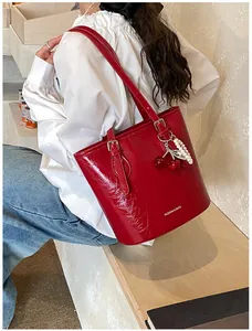 Close-up of red patent leather tote bag with cherry charm and pearl strap detail