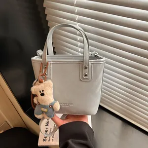 Sac seau en cuir bleu clair avec breloque d'ours en peluche et bandoulière amovible