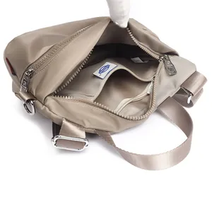 Minimalist khaki nylon crossbody bag showing spacious interior with blue logo label